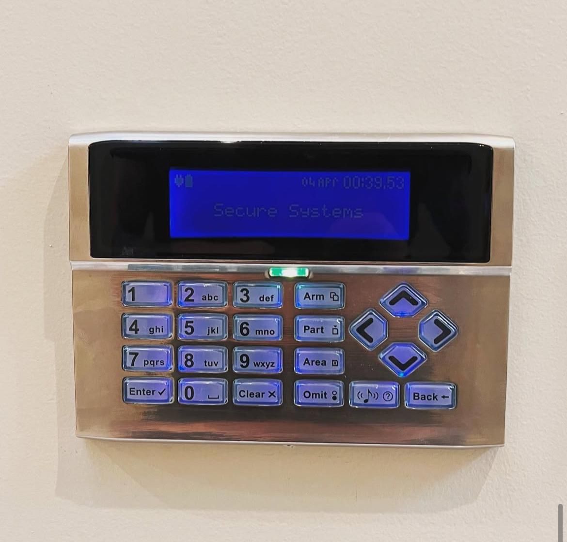 An alarm keypad showing the Secure Systems name on its display, fitted to an interior wall.