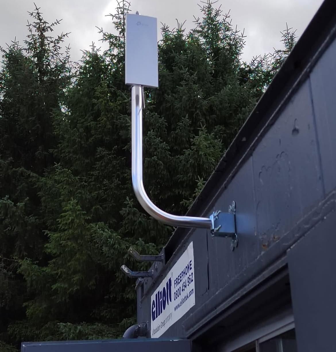 A pan-tilt-zoom camera mounted at the corner of a building beside a CCTV warning sign.